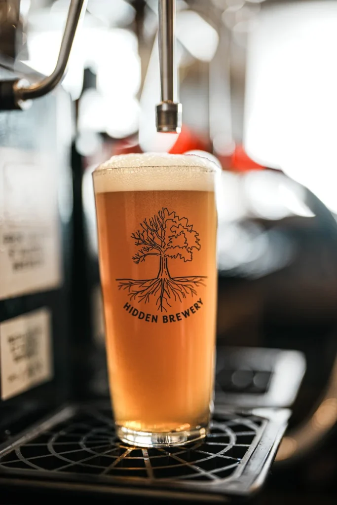 The Falcon Inn Beer from Hidden Brewery on tap. Tree logo visible on the glass.